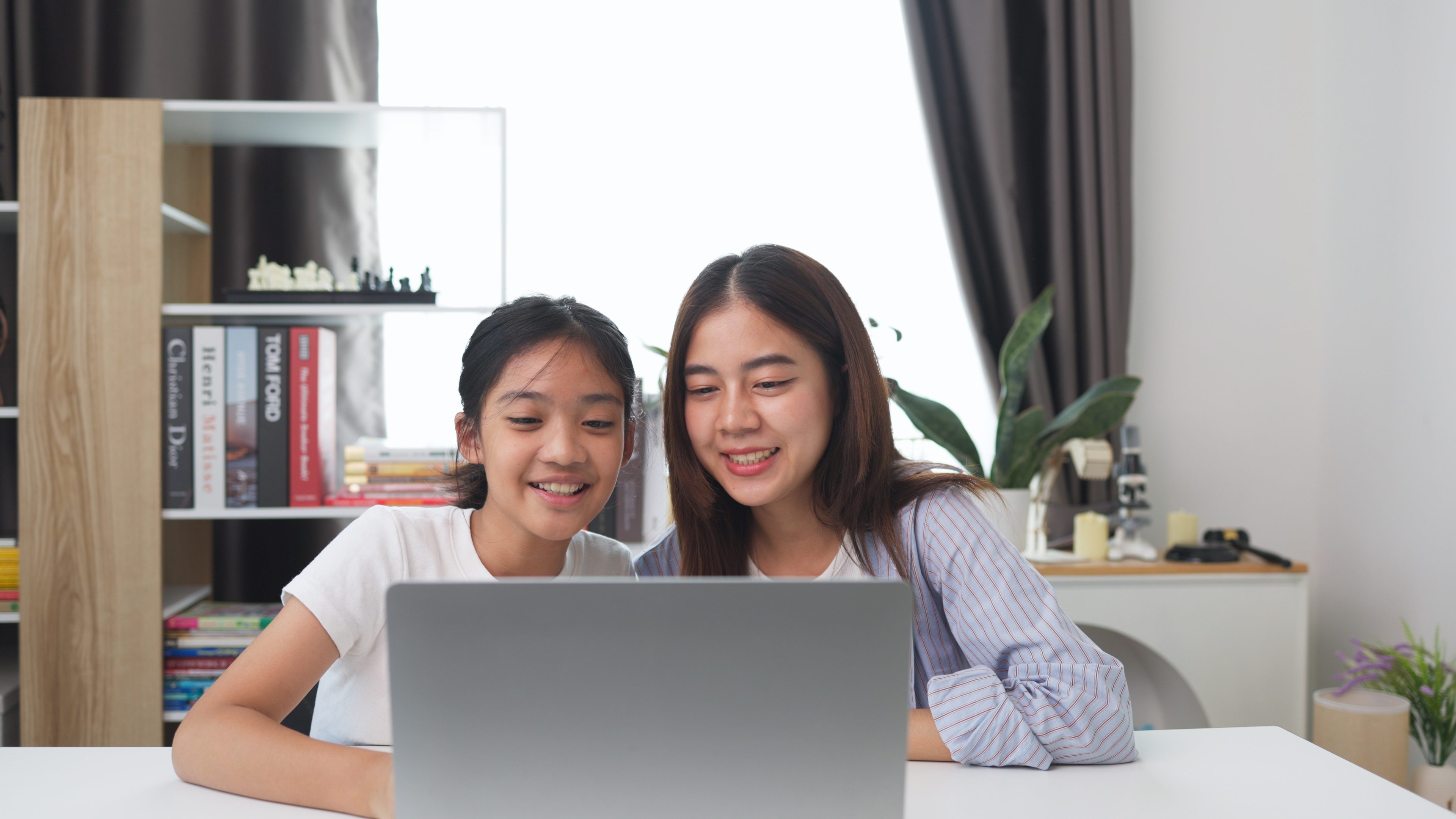 Parent guiding daughter on a laptop